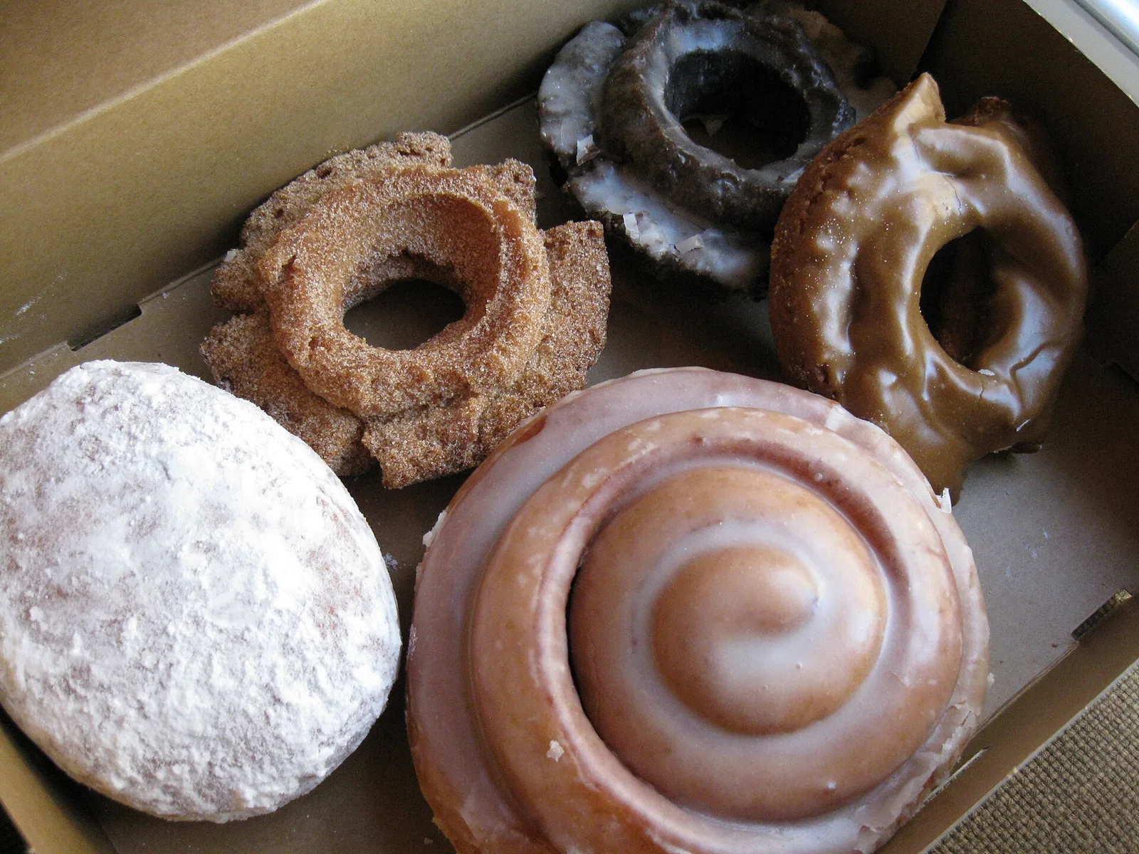 A box of doughnuts with a glazed cinnamon roll. The photo was not taken at a Wilmington bakery.