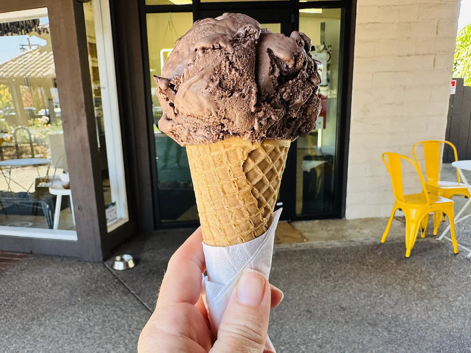 A chocolate chip ice cream cone held outside an ice cream shop. The photo was not taken in Wilmington.