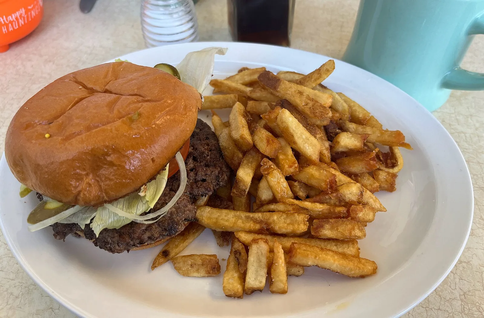 A burger with lettuce, onion and pickles beside a plate of fries. The photo was not taken at a Wilmington restaurant.